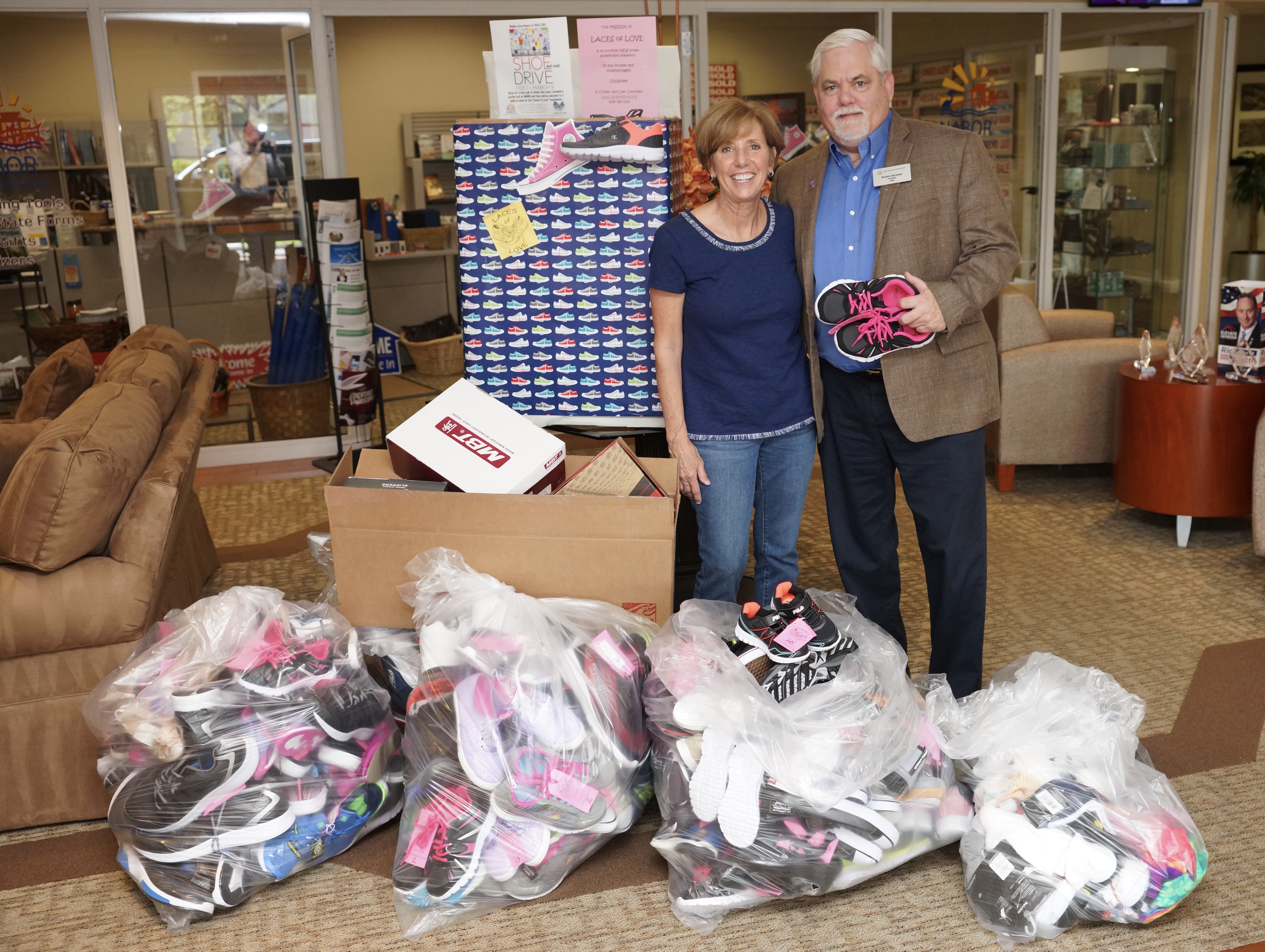 People standing in front of shoes collected for the Shoe Drive
